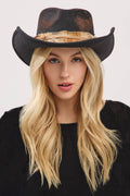 Vintage distressed black cowgirl hat with a shapeable design and a feather detail, worn by a model with long blonde hair.