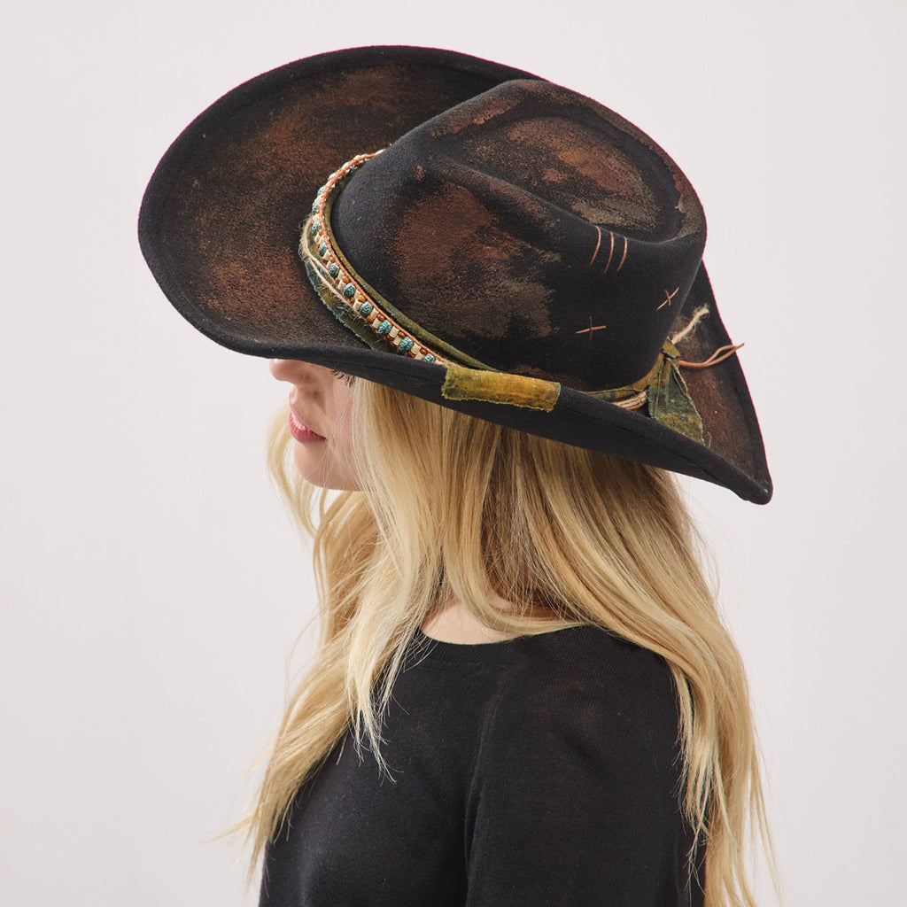 Rustic shapeable cowgirl fedora hat with a distressed fabric band, flexible brim, and vintage charm worn by a model.