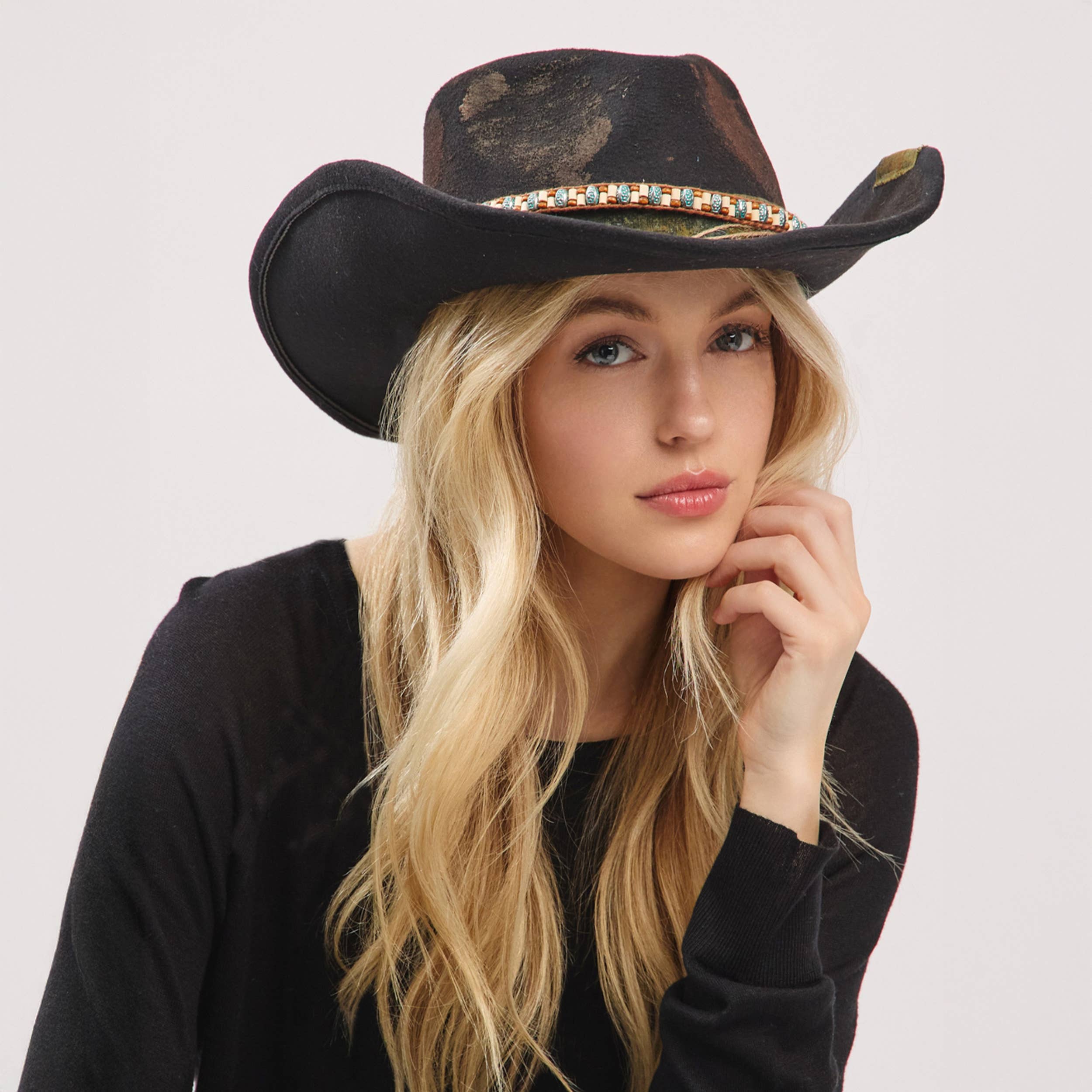 Black distressed cowgirl fedora hat with a flexible brim and a decorative band, worn at a slight angle.
