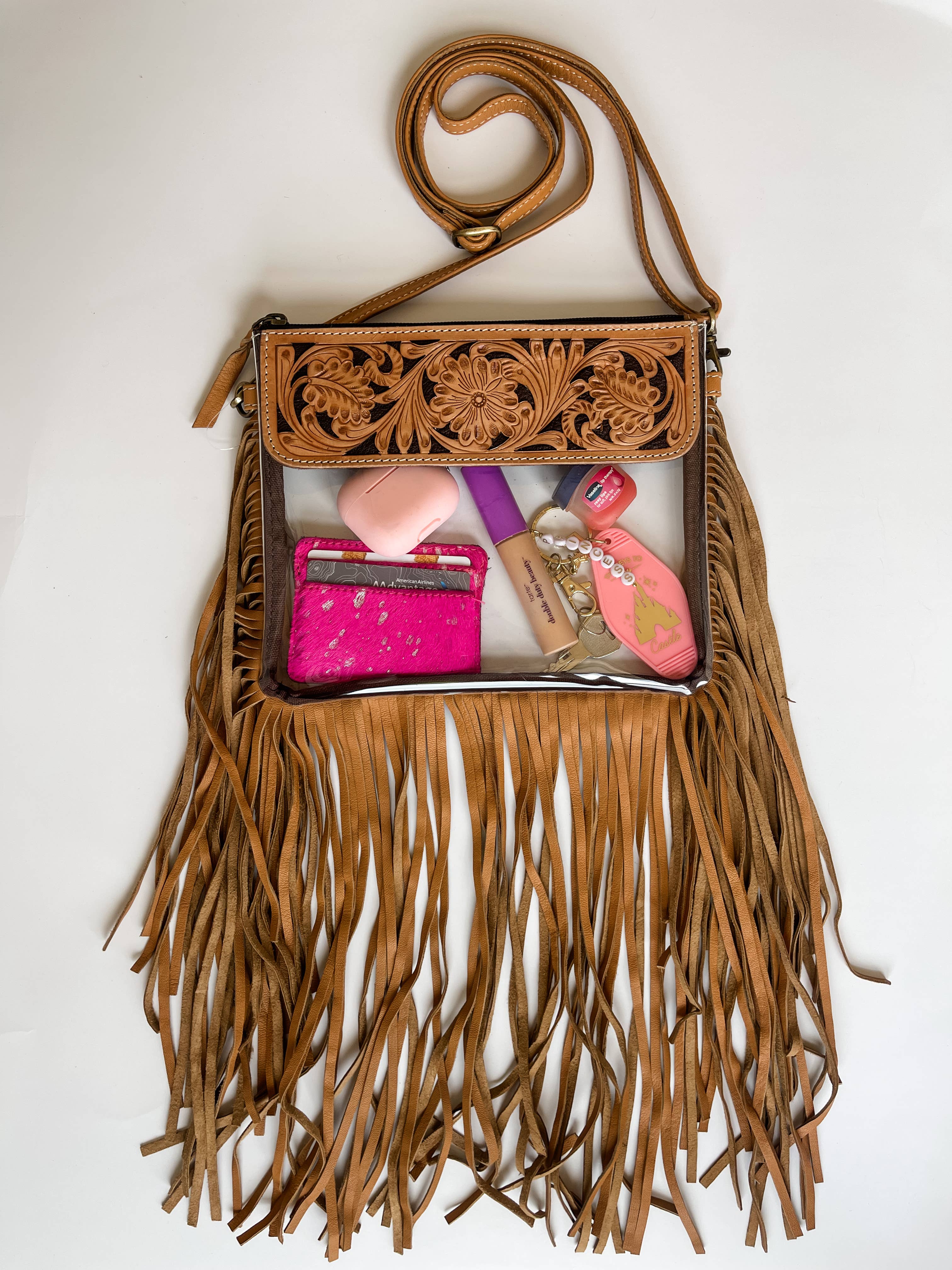 Boho-style clear crossbody purse with hand-tooled leather and fringe detail, featuring a secure snap closure and adjustable strap.