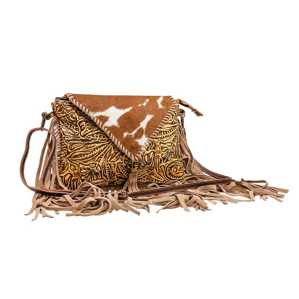 Brown leather and hair-on-hide bag with intricate patterns, fringe details, and a stylish triangular flap.