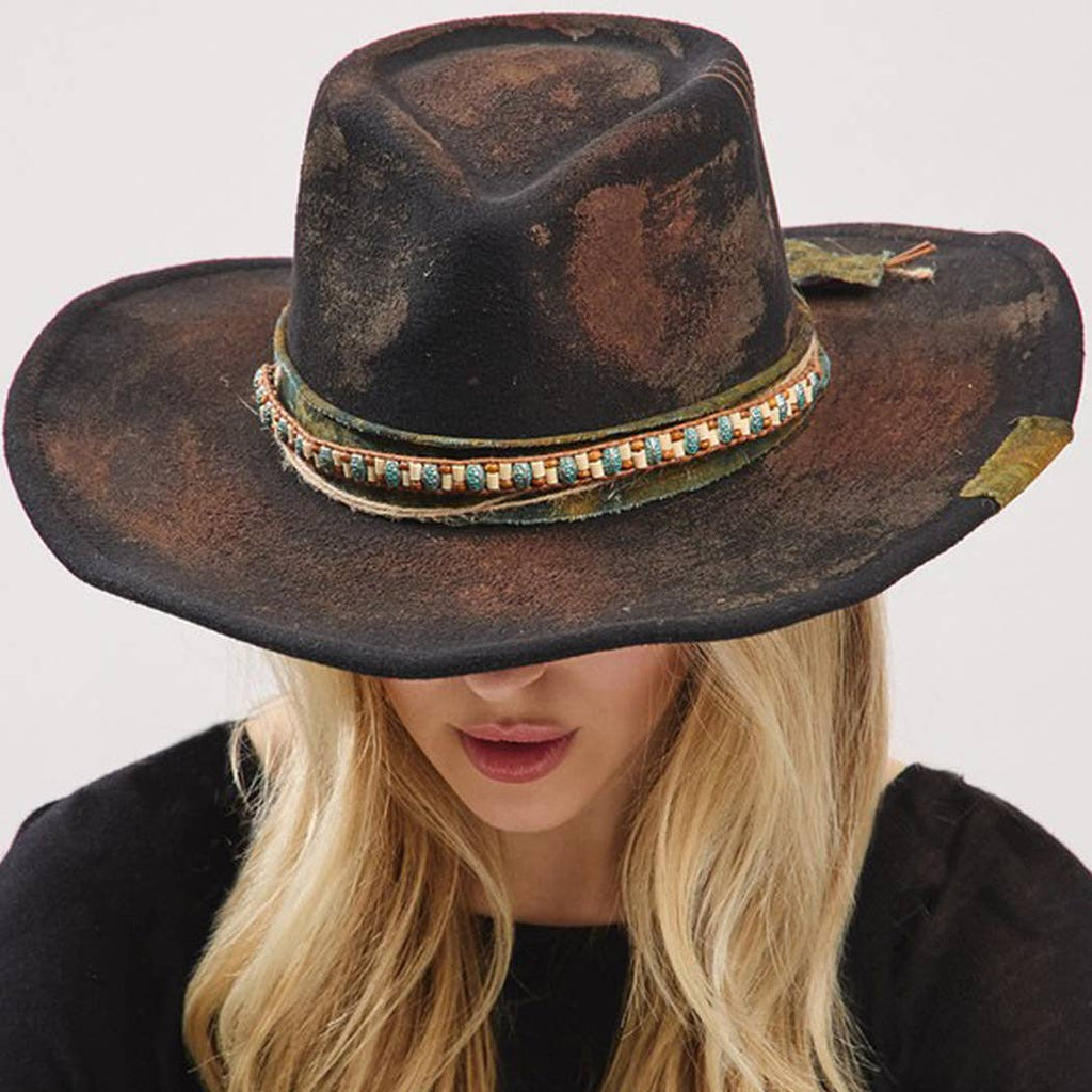 Vintage versatile shapeable cowgirl and fedora hat with distressed fabric band and decorative bow detail worn by woman