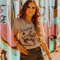 Woman wearing Cowgirl Up Graphic Tee with horse riding cowboy design and vintage rodeo style