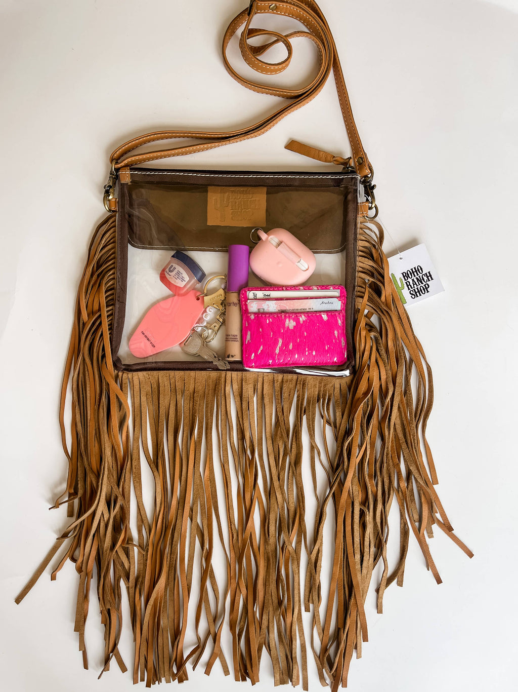 Clear crossbody purse featuring genuine hair-on cowhide, brown leather, and long fringe detailing, suitable for concerts.