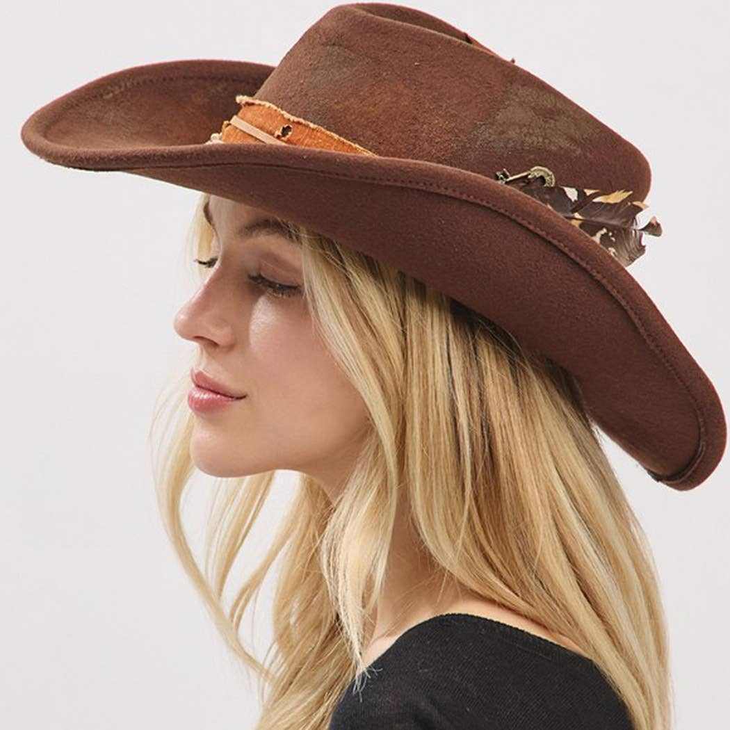 Vintage versatile shapeable brown cowgirl and fedora hat with feather and distressed fabric band worn by woman