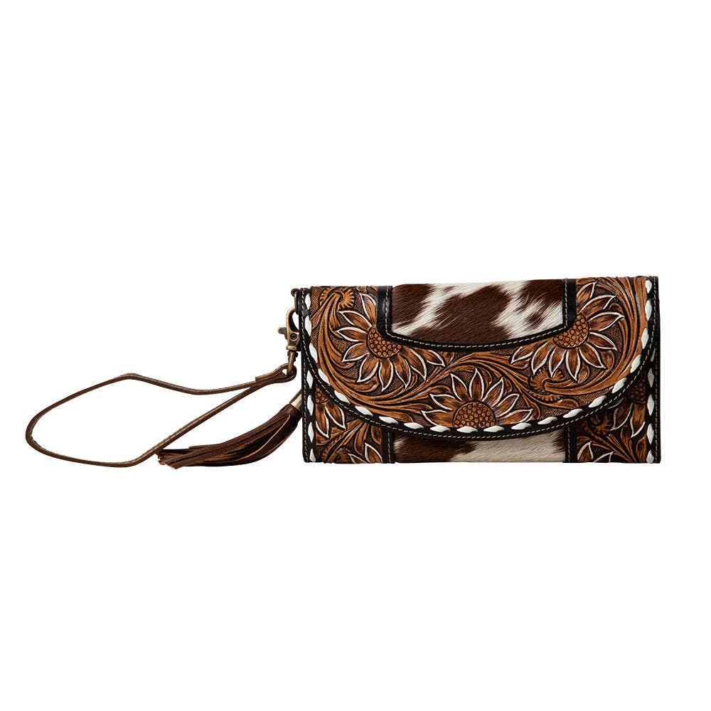 Hand-tooled wallet featuring floral designs in brown leather and hair-on cowhide with a snap closure and wristlet strap.