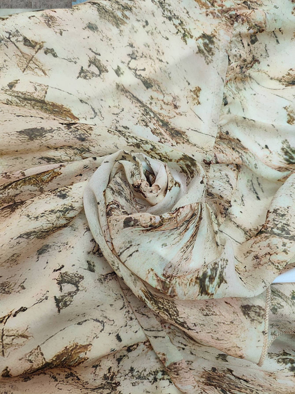 Layered fabric with a floral print in soft earth tones, featuring natural leaf and wood-like patterns.