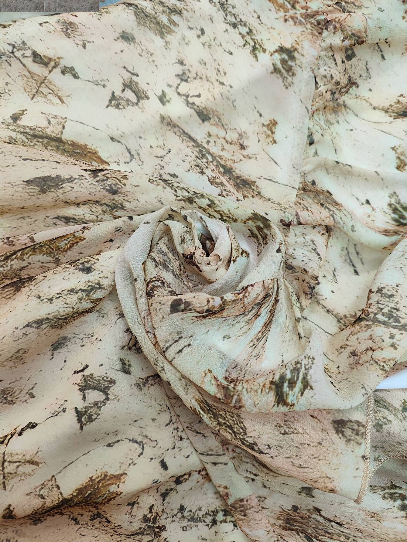 Layered fabric with a floral print in soft earth tones, featuring natural leaf and wood-like patterns.