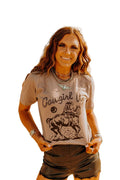 Woman wearing brown Cowgirl Up Graphic Tee with horse riding cowboy design in urban setting