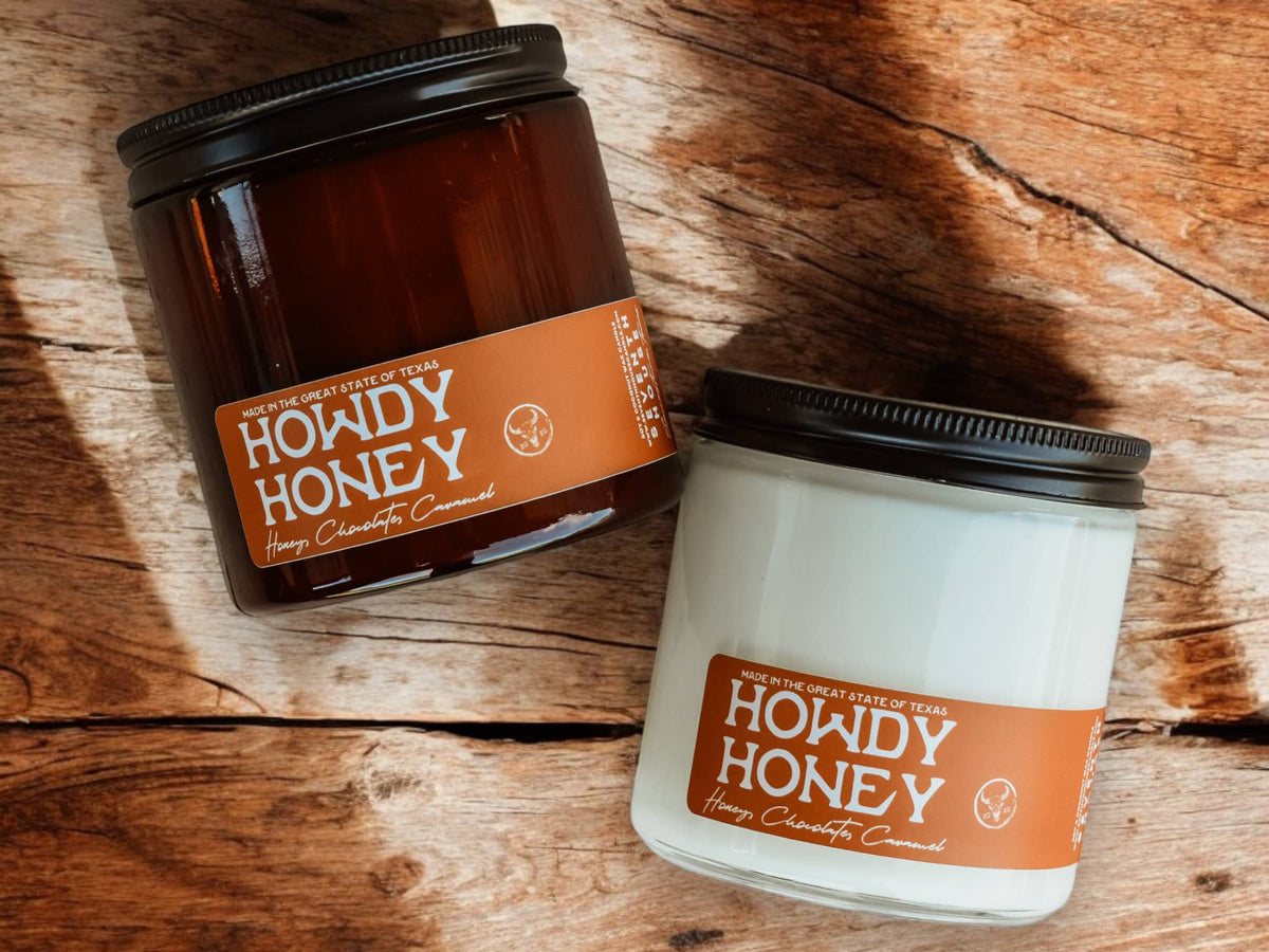 Howdy Honey vanilla caramel honey scented candles in amber and clear jars on wooden surface