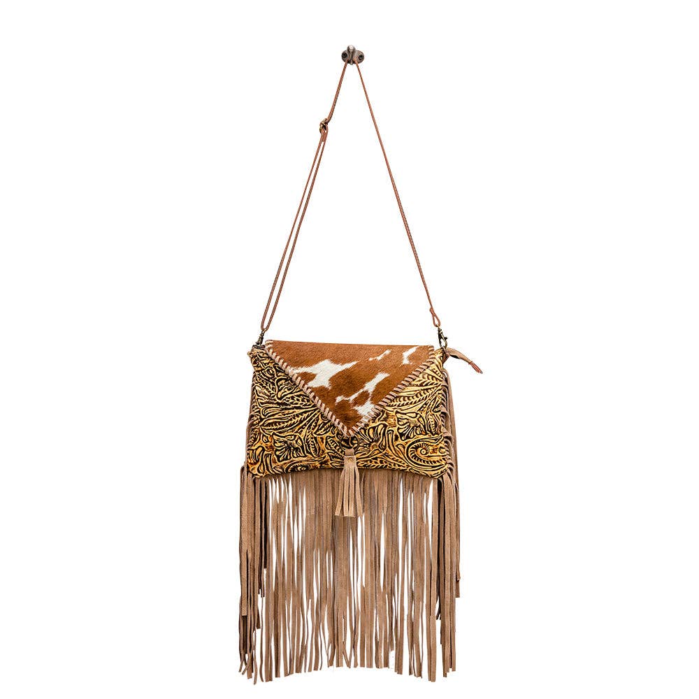 Brown leather and hair-on-hide bag with floral embossing, fringed bottom, and adjustable shoulder strap.