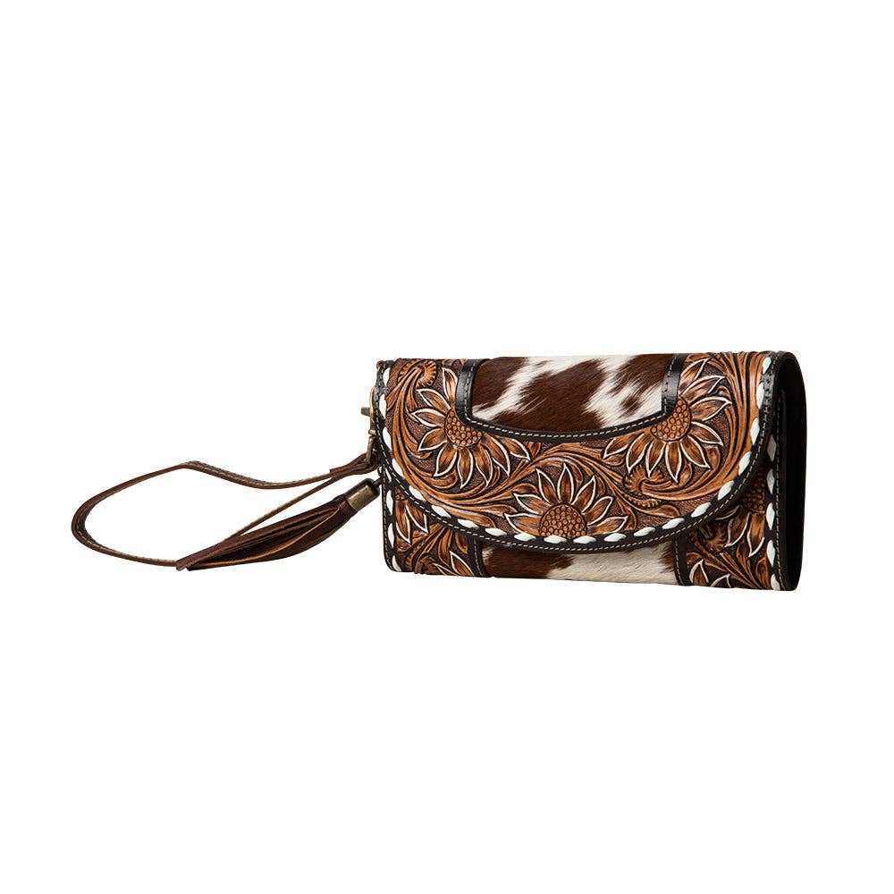 Hand-tooled wristlet wallet featuring a sunflowers design with brown hair-on cowhide. Includes a leather wrist strap.