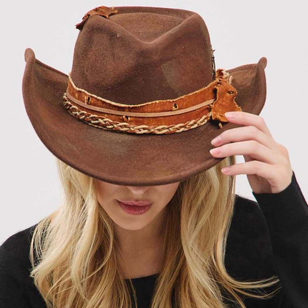 Vintage versatile shapeable brown cowgirl and fedora hat with feather and distressed fabric band worn by woman