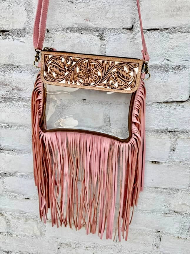Boho-inspired crossbody bag with clear vinyl, floral tooled flap, and pink fringes at the bottom.