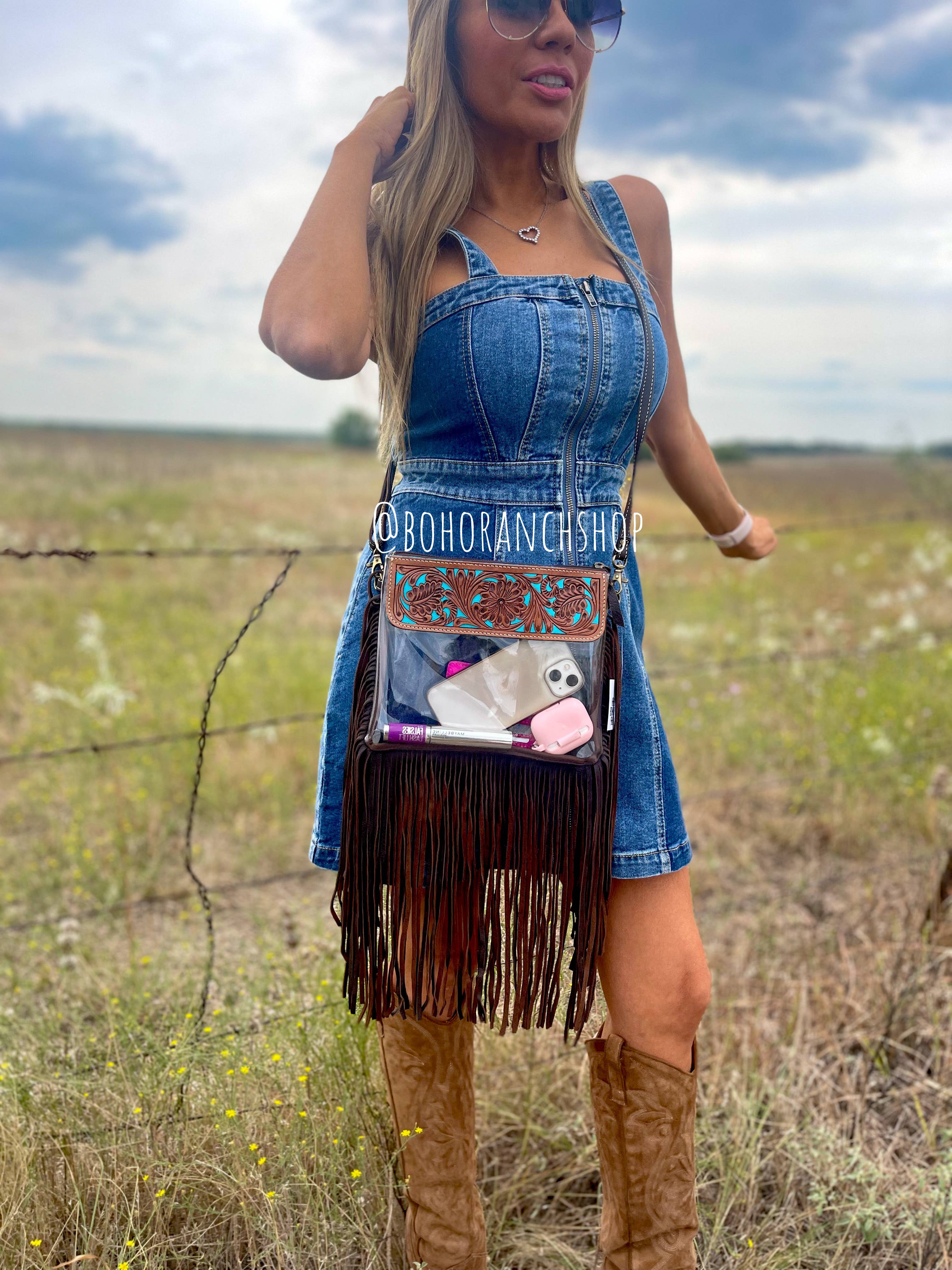Clear crossbody purse featuring a genuine hair-on cowhide design, with fringe detailing, worn over a denim dress.