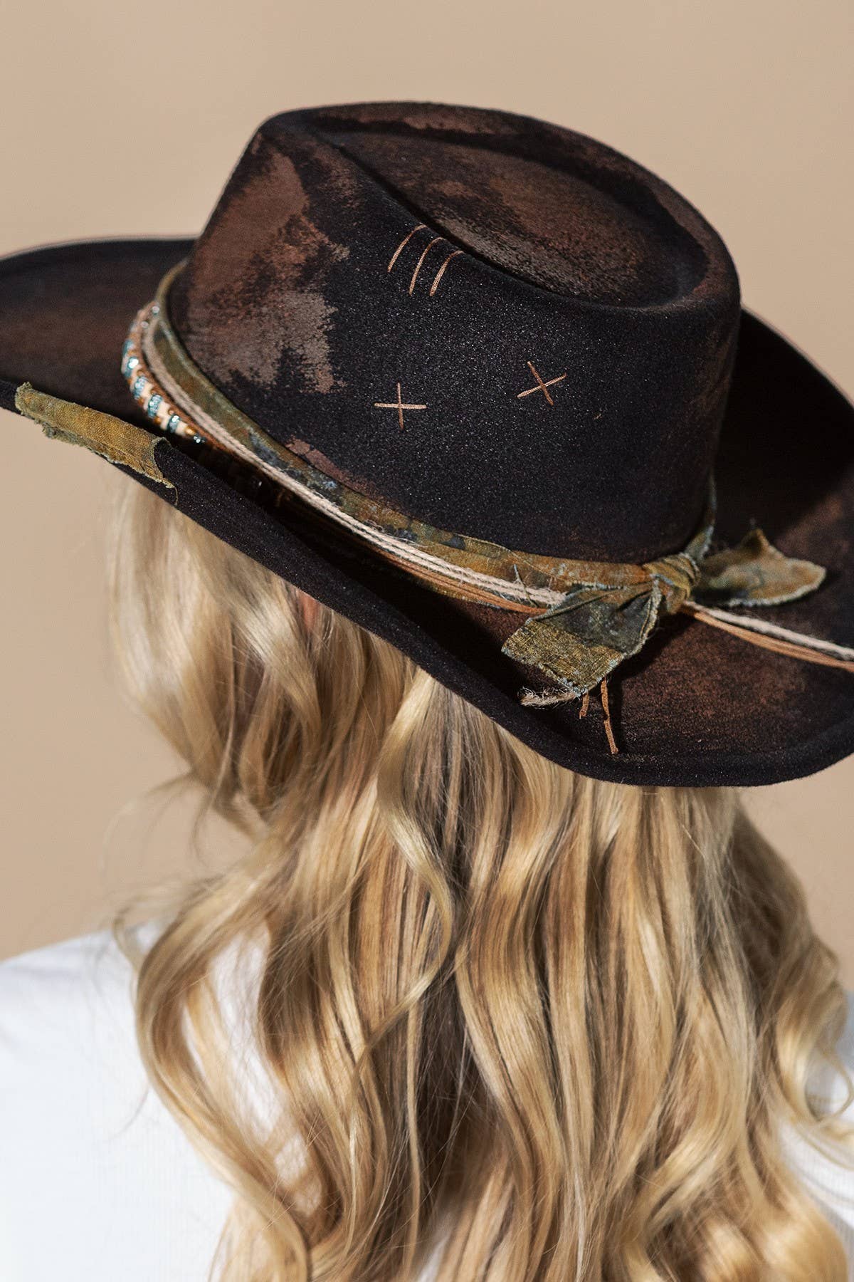 Distressed black shapeable cowboy hat with a turquoise beaded band and weathered fabric wrap, styled for a vintage look.