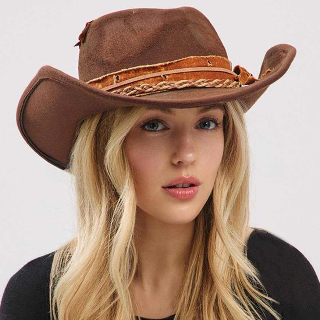 Vintage versatile shapeable cowgirl and fedora hat with feather and distressed fabric band worn by woman