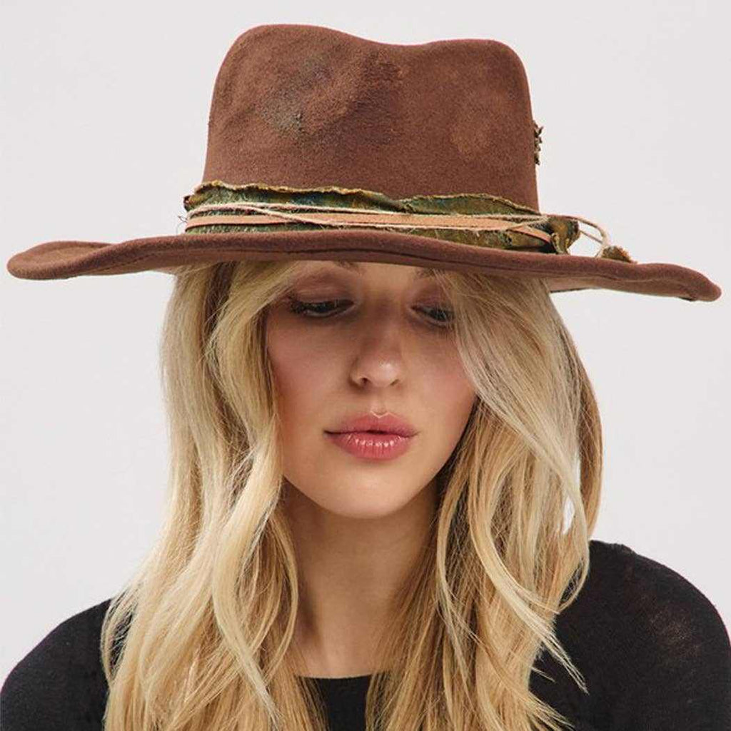 Woman wearing vintage shapeable cowgirl and fedora hat with distressed fabric and suede band