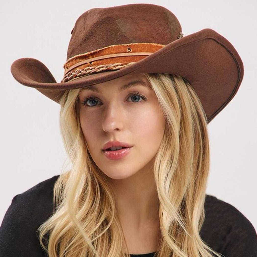 Vintage versatile shapeable brown cowgirl and fedora hat with feather and distressed fabric band worn by woman