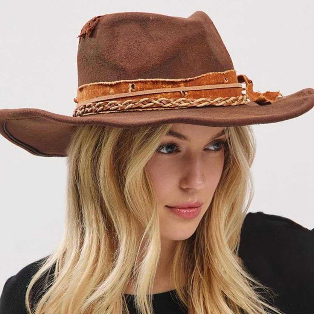 Vintage versatile shapeable cowgirl and fedora hat with feather and distressed fabric band worn by woman