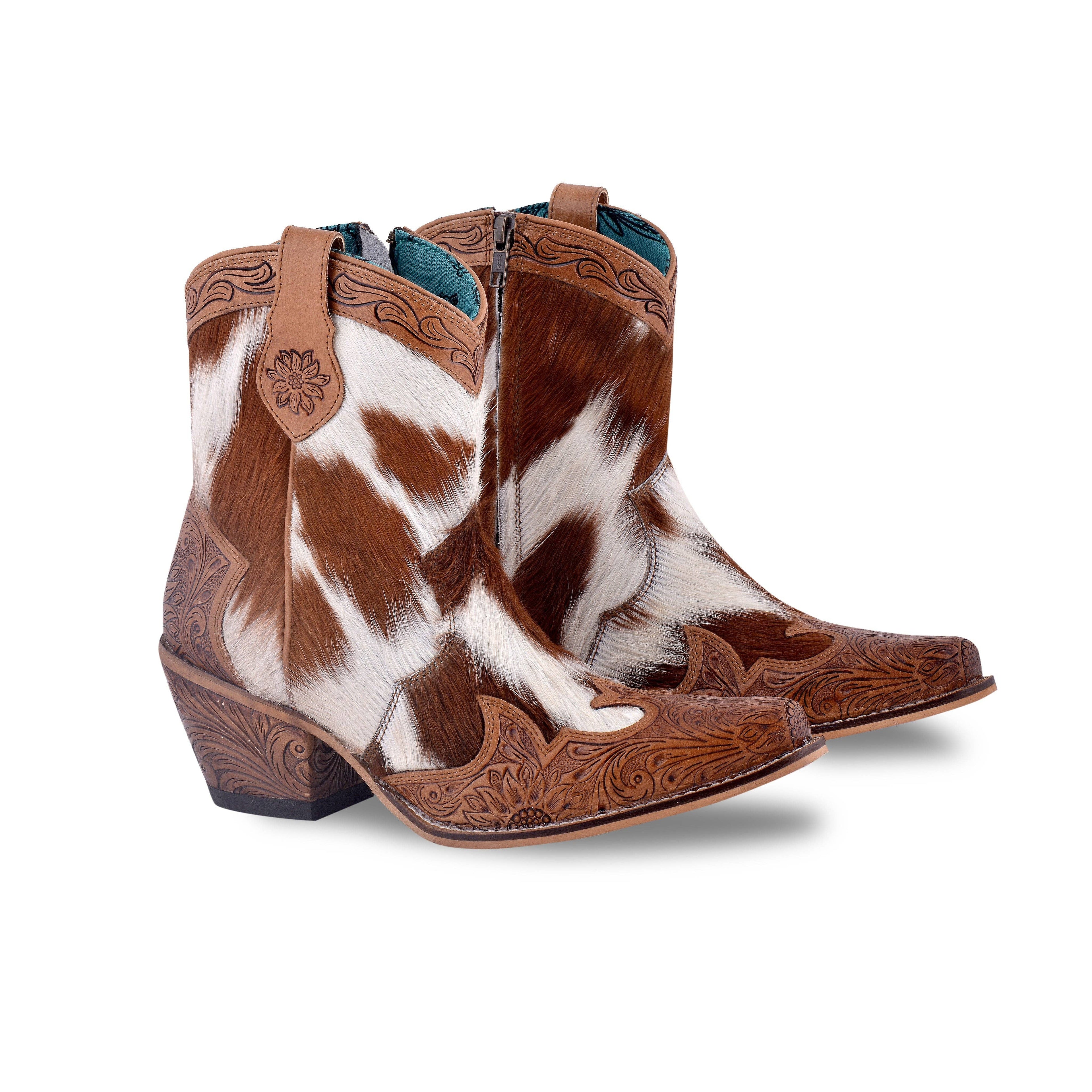 Hand-tooled leather boots featuring a hair-on hide design in brown and white. Snip toe with decorative engraving.