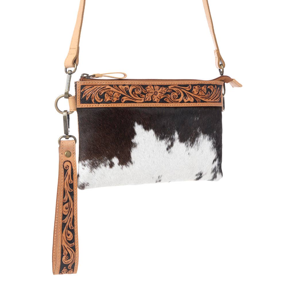 Compact leather bag featuring brown and white hairon panels, hand-tooled detailing, and an adjustable strap.