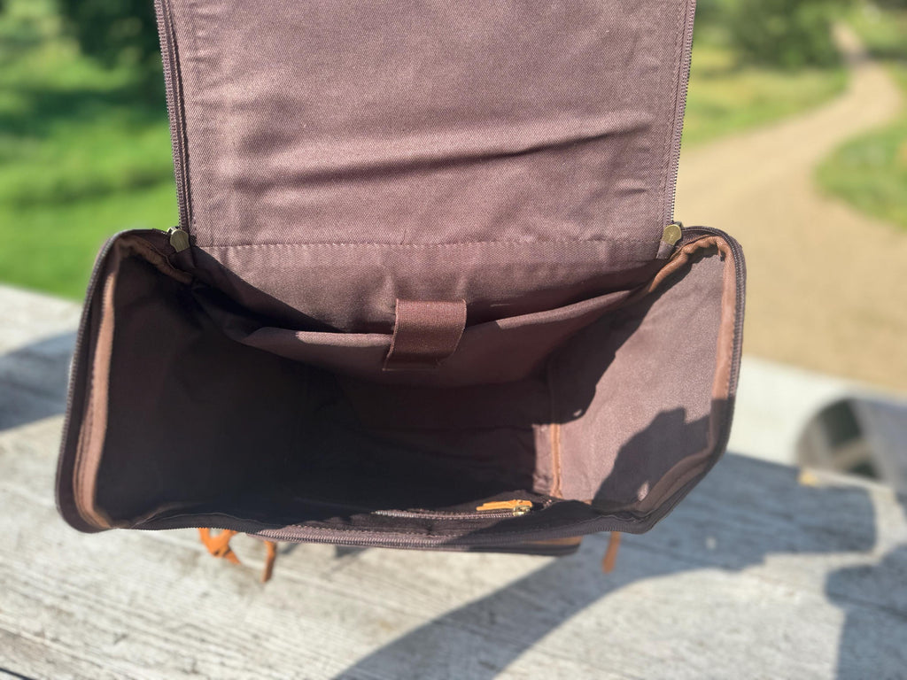 Genuine leather backpack diaper bag with a spacious main compartment, featuring a zip closure and interior pockets.